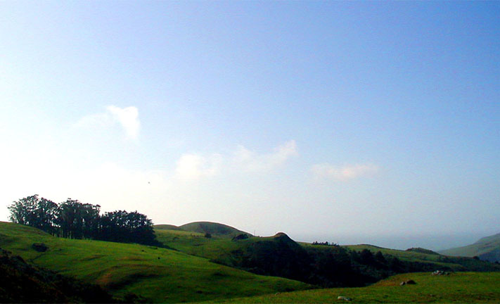 on high terrain,, green sloping hills against blue sky
